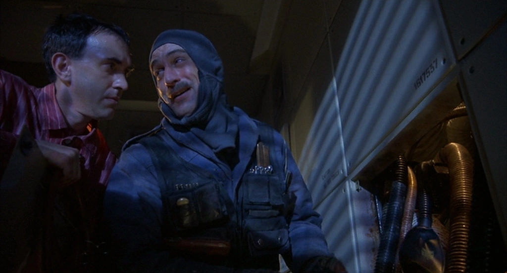 Robert De Niro as Harry Tuttle beside exposed ducts in Brazil (1985).
